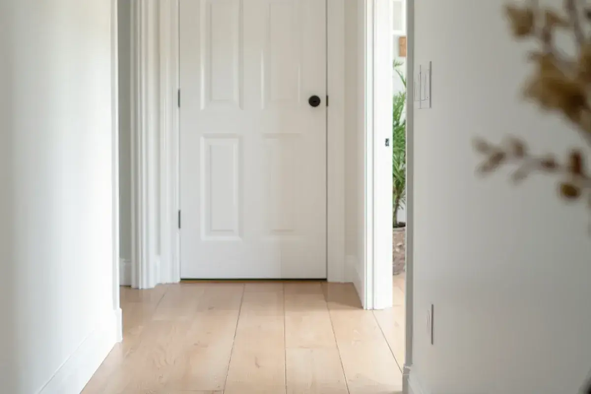 T-molding joining two vinyl plank rooms at a doorway in a Jacksonville, FL hallway